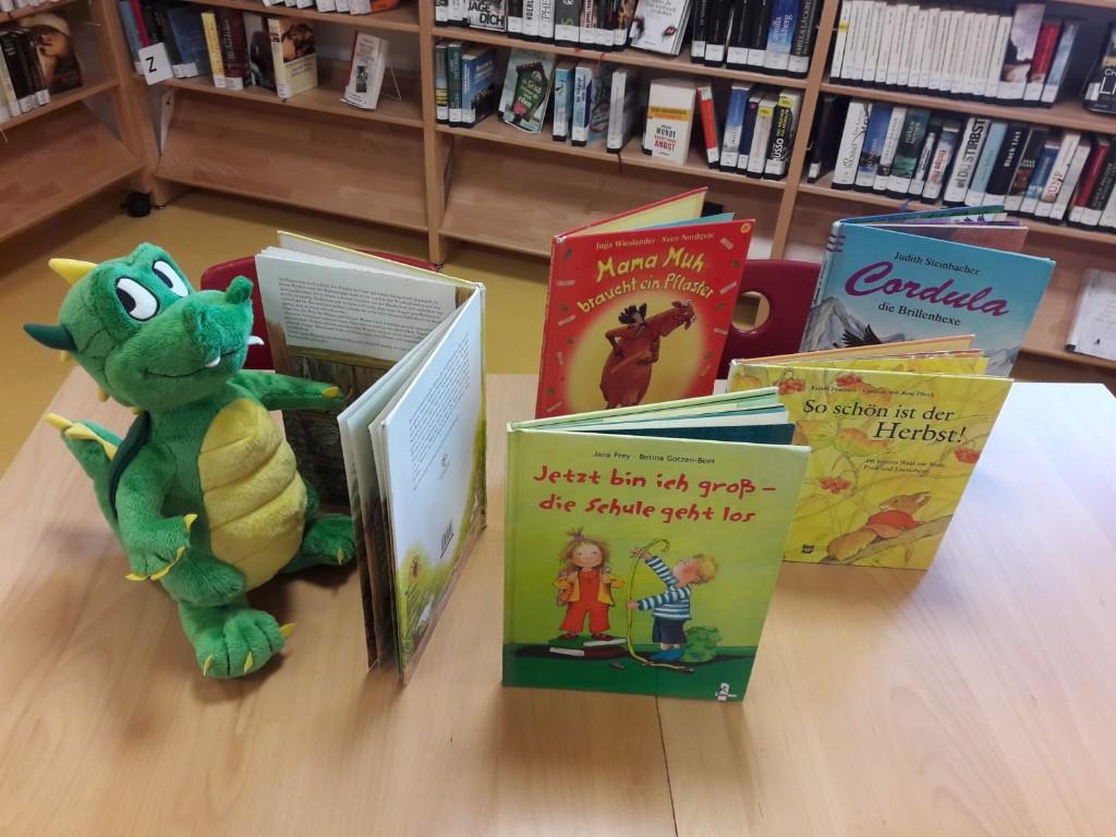 Stofftier Drache mit Kinderbüchern auf einem Tisch